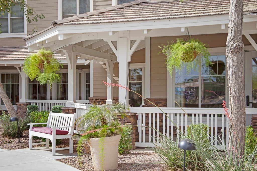 A cozy porch with a bench surrounded by potted and hanging plants.