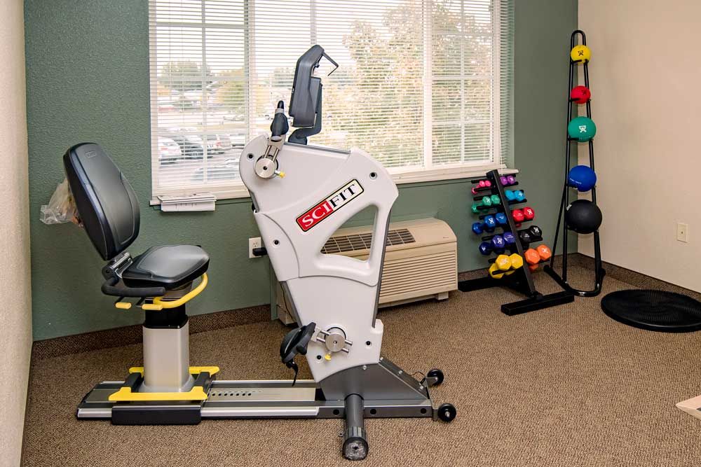 A therapy room with exercise equipment and a rack of colorful weights.