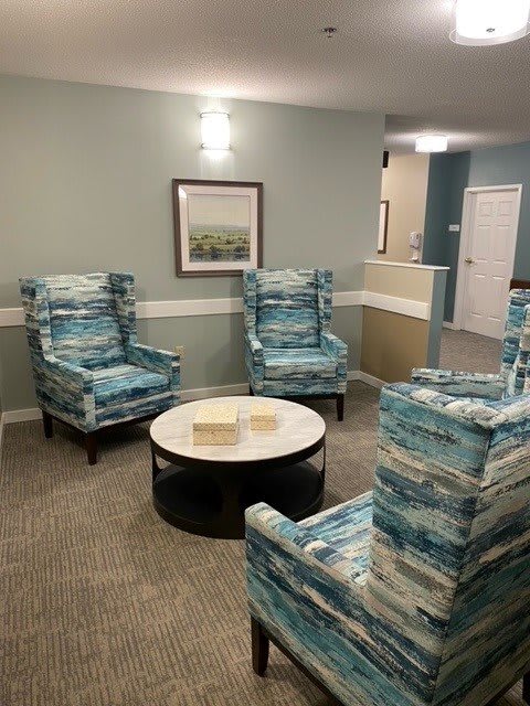 A cozy waiting room with patterned armchairs and a round coffee table.
