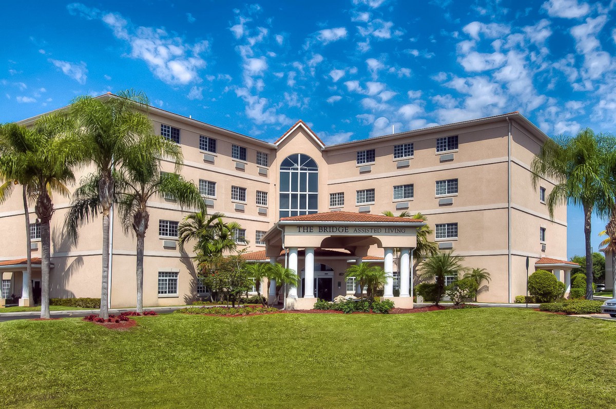 A hotel building with a grand entrance, surrounded by palm trees and set against a blue sky.
