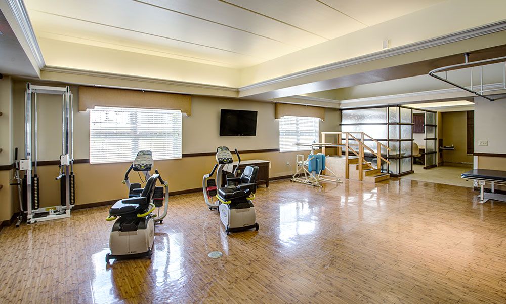 A spacious rehabilitation center with therapy chairs and exercise equipment.
