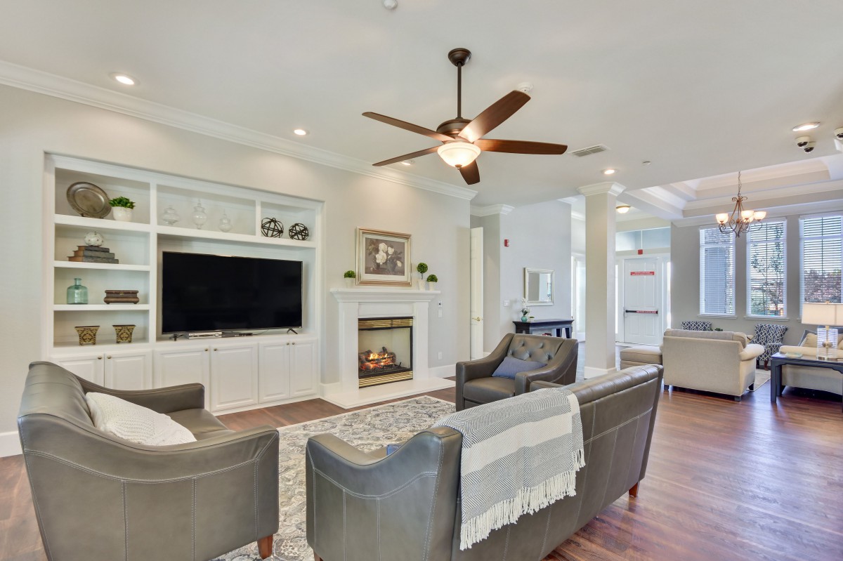 A modern living room featuring a fireplace, ceiling fan, and TV.