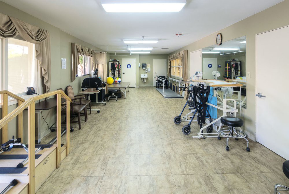 An empty rehabilitation center with physical therapy equipment and exercise aids.