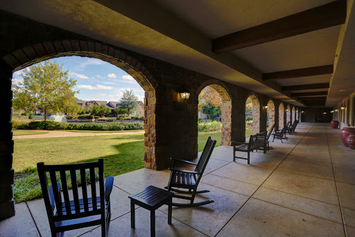 A serene outdoor porch with rocking chairs, offering a peaceful view of the landscaped garden.