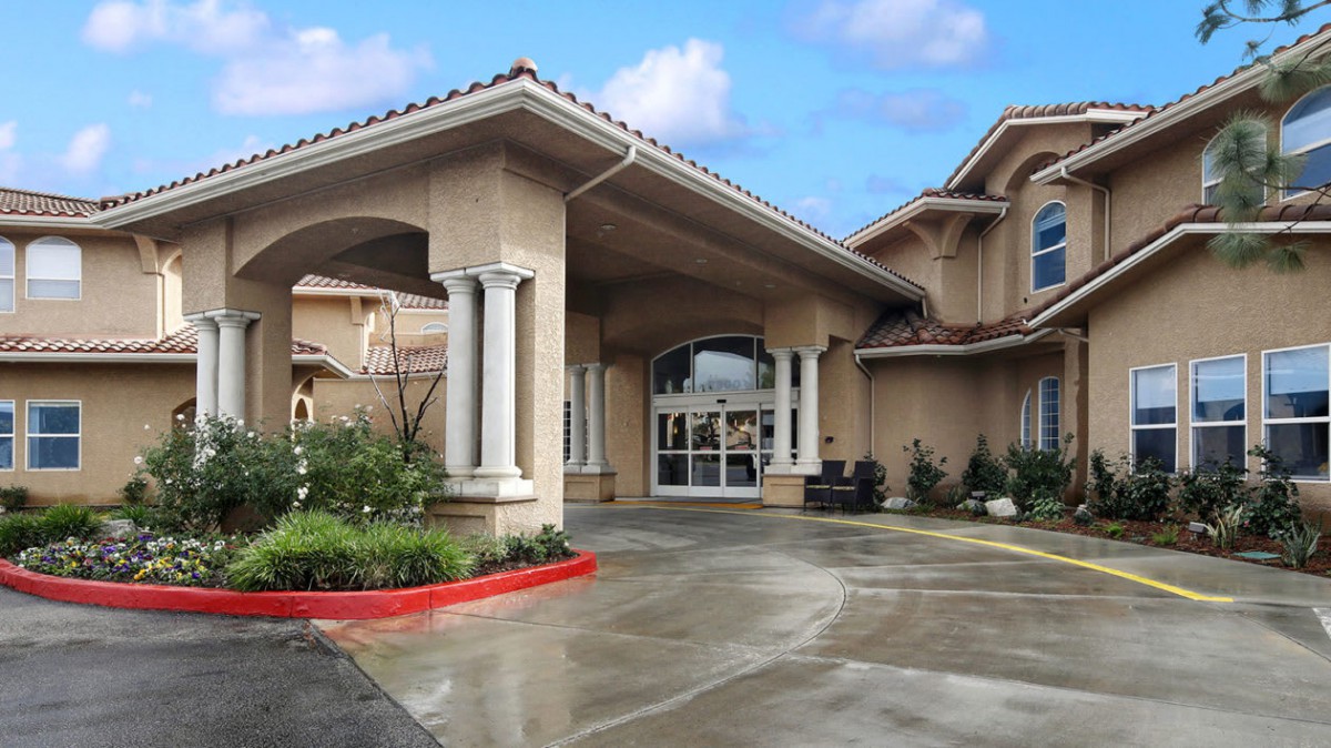 A residential building with a covered driveway entrance and columns.