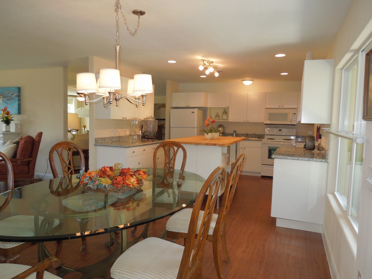 A modern kitchen and dining area with wooden chairs and a glass table.
