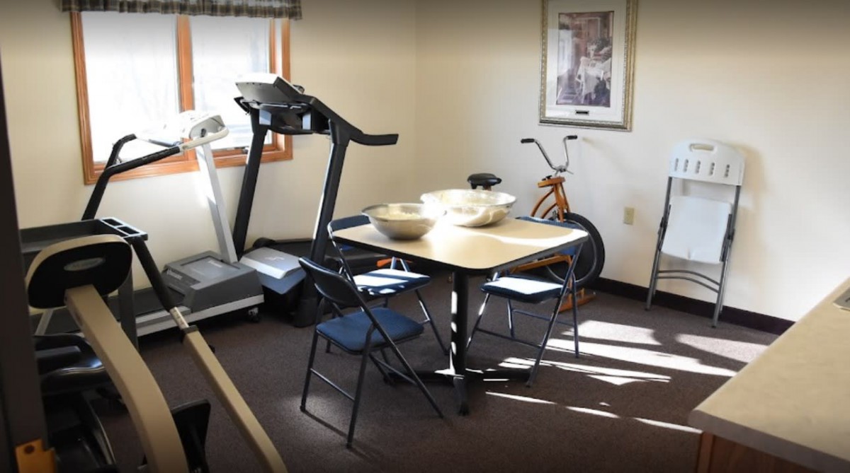 A room with exercise equipment and a table with chairs.