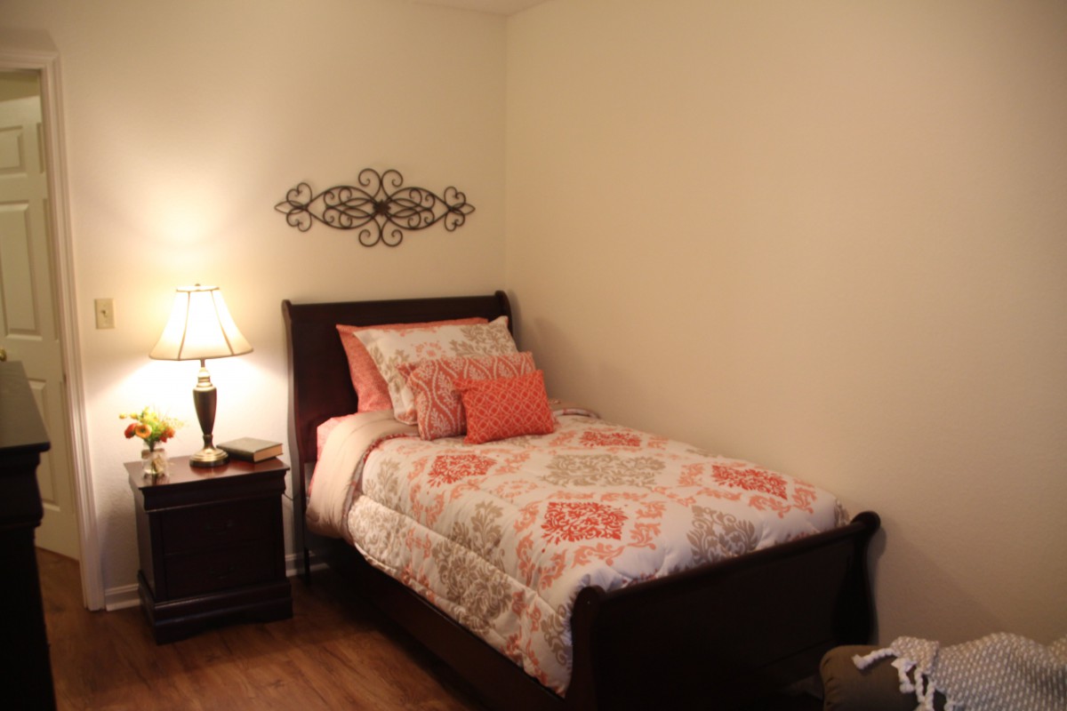 A cozy bedroom with a single bed, decorative pillows, and warm lighting.