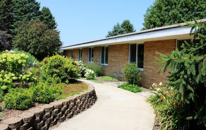 A brick house with a well-maintained garden and a curving pathway.