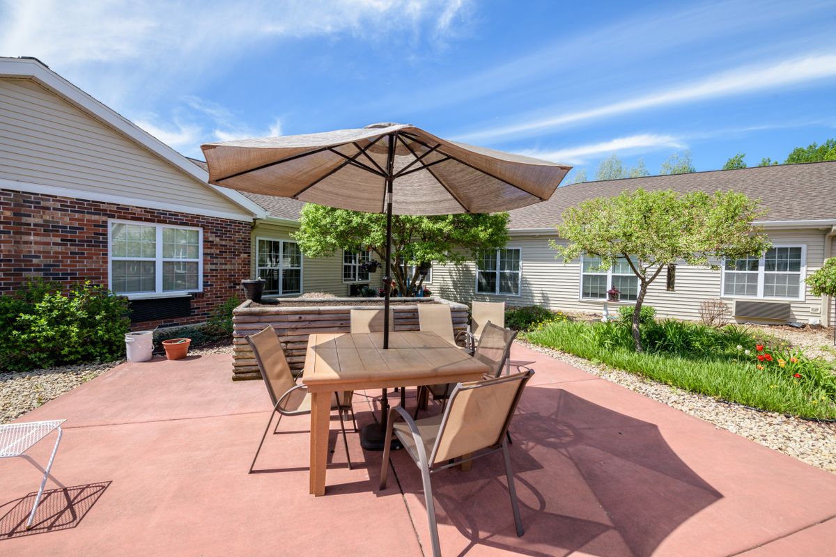 A sunny backyard patio with a table and umbrella for outdoor seating.