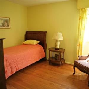 A cozy bedroom with a single bed, wooden furniture, and bright yellow walls.