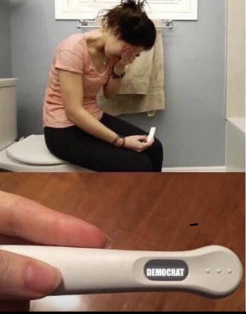 A woman reacts emotionally while holding a pregnancy test in a bathroom.