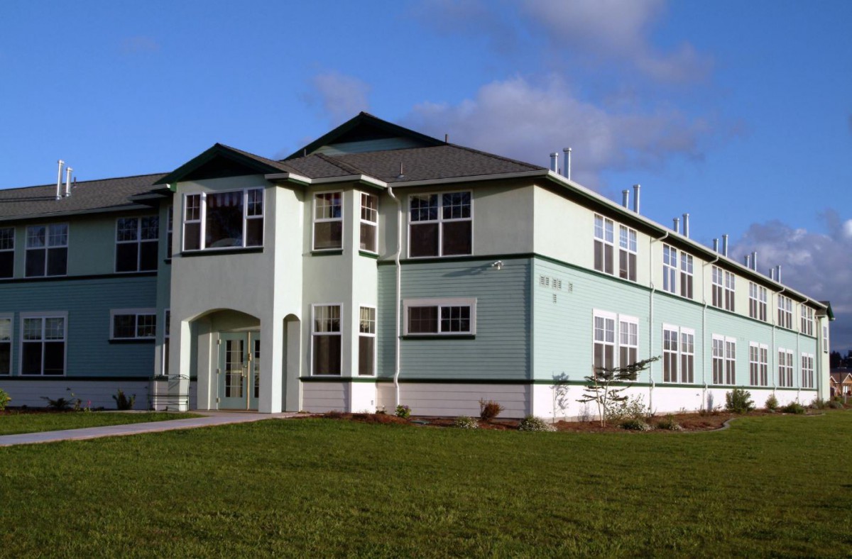 A two-story residential house with a well-maintained lawn and clear sky in the background.