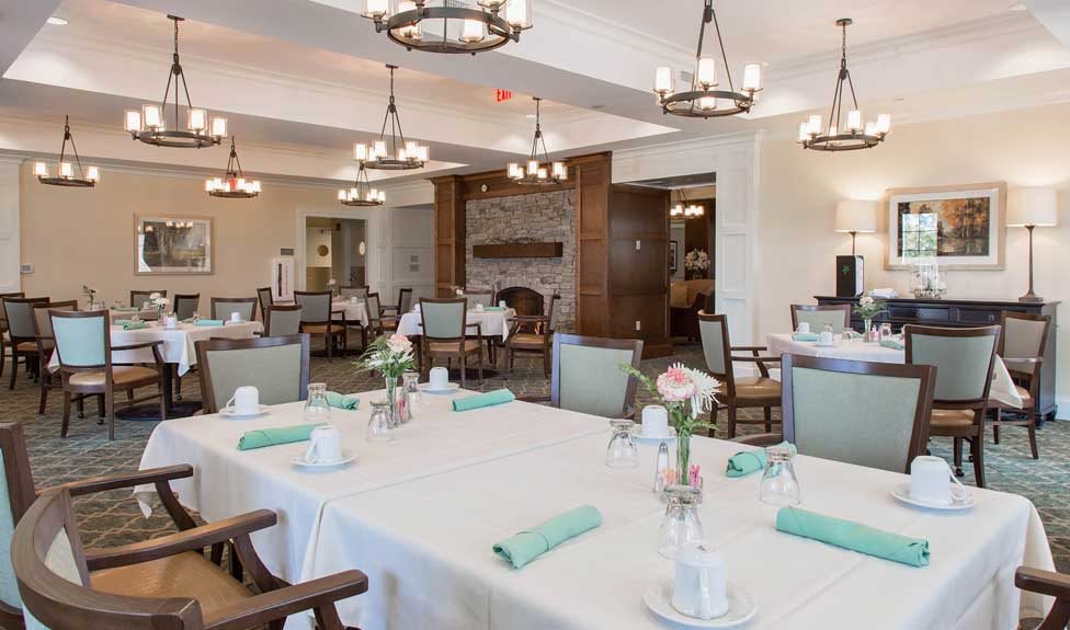 An elegantly set dining area with neatly arranged tables and chandeliers.