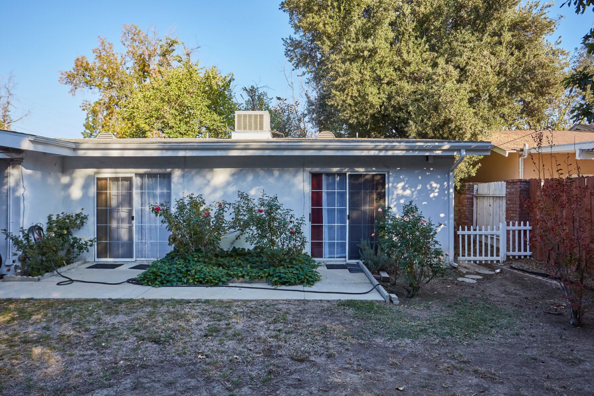 A small house with a garden in front and surrounded by trees.