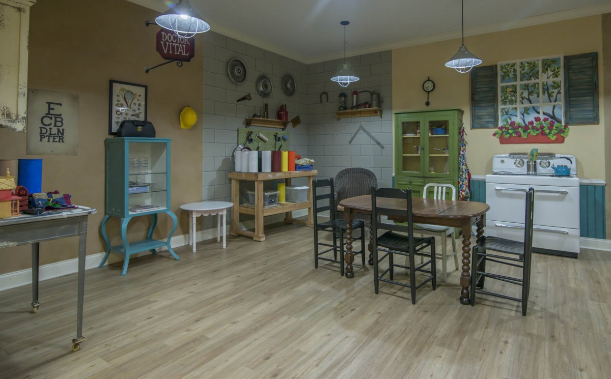 A cozy dining area with a mix of chairs around a wooden table, surrounded by shelves and decorative items.