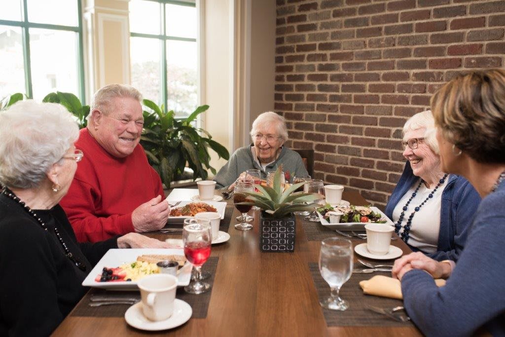 A group of seniors enjoying a meal together at a dining table.