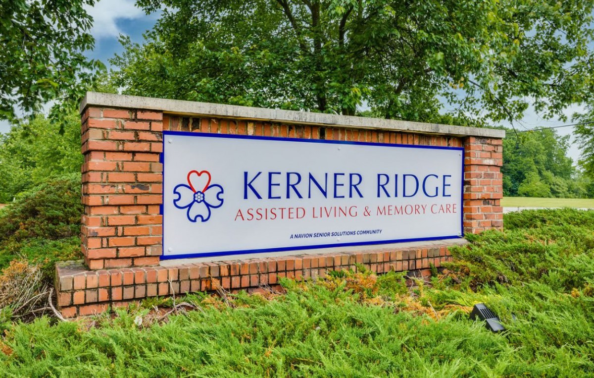 Sign for Kerner Ridge Assisted Living & Memory Care on a brick wall surrounded by greenery.