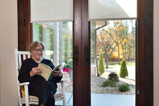 A person enjoying a peaceful moment reading indoors with a view of the autumn landscape outside.