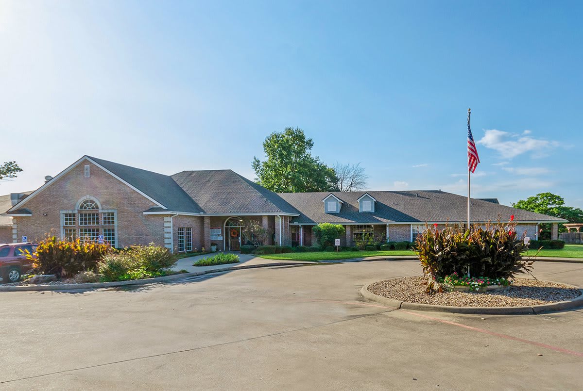 A large residential building with a driveway and an American flag in front.