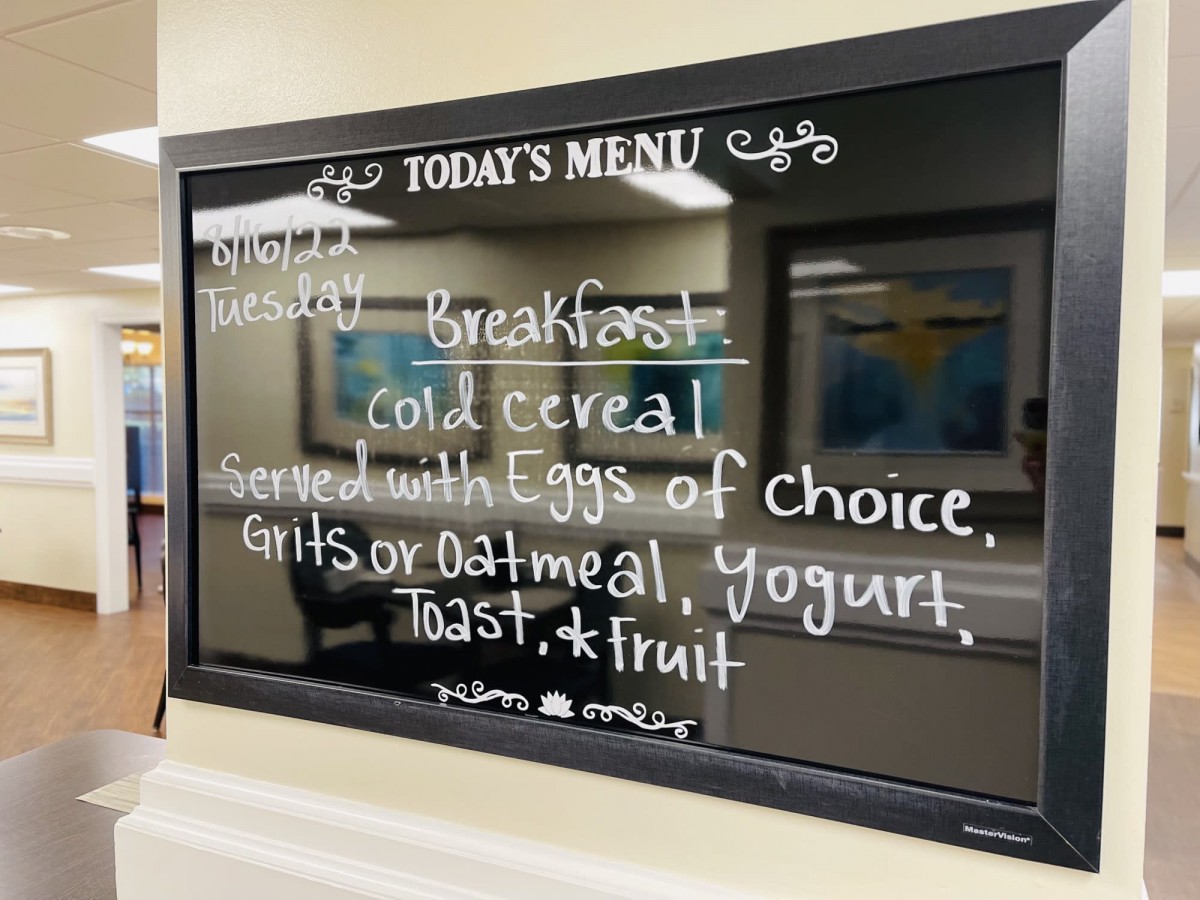 Breakfast menu displayed on a chalkboard, offering cereal, eggs, grits or oatmeal, yogurt, toast, and fruit.