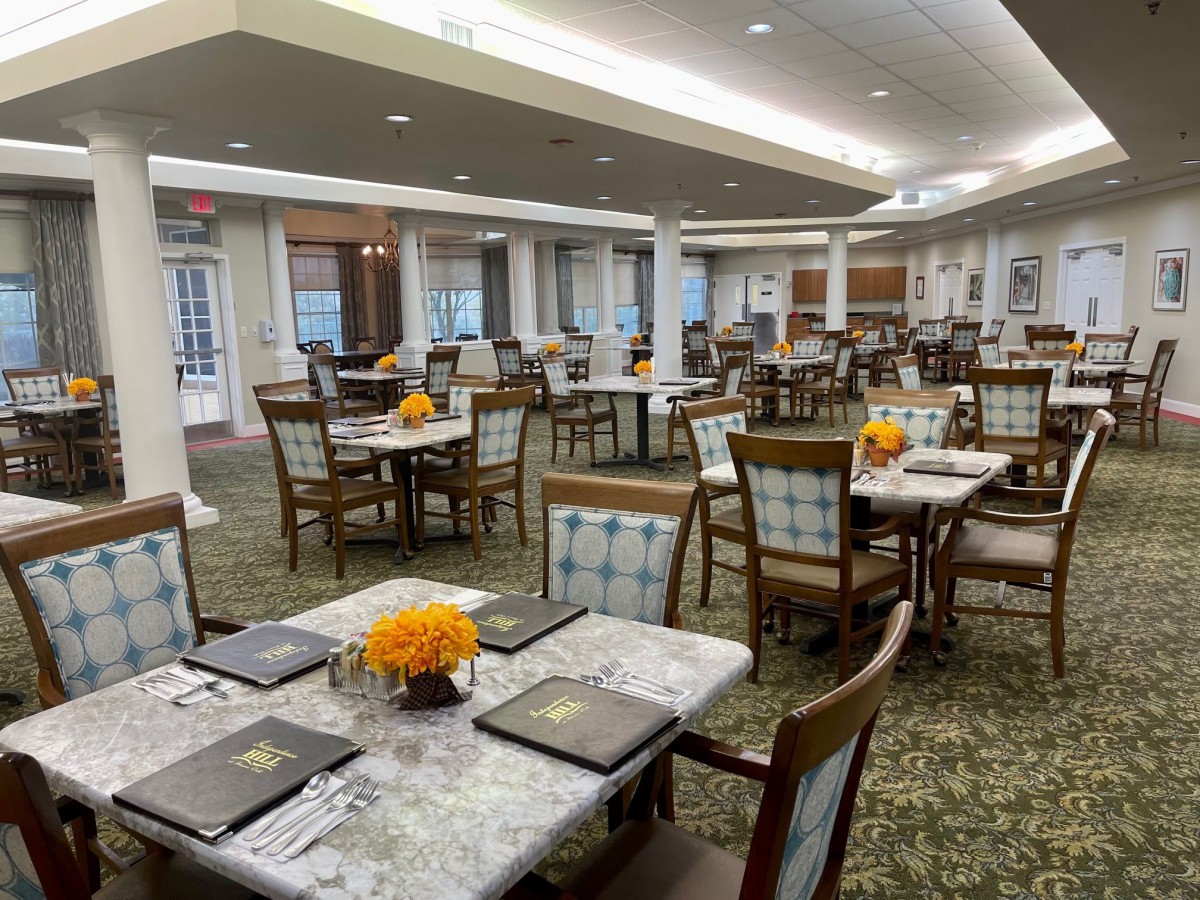 An elegant dining room with neatly set tables and floral decorations.