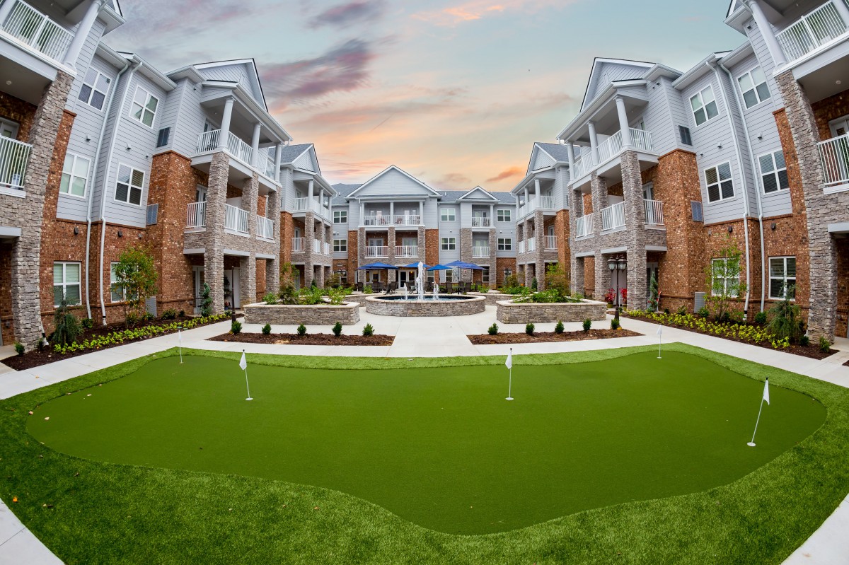 A modern apartment complex with a landscaped courtyard at sunset.