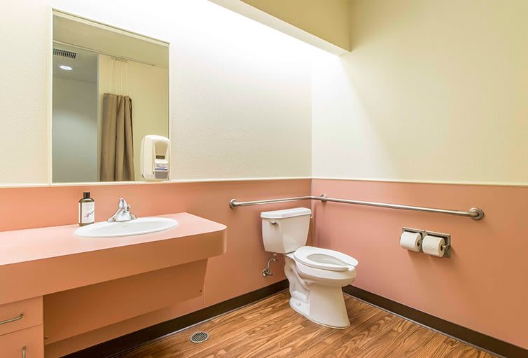 A clean, handicap-accessible bathroom with a toilet, sink, and grab bars.