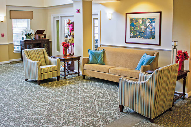 A cozy living room with a sofa, two armchairs, and a coffee table on a patterned carpet.