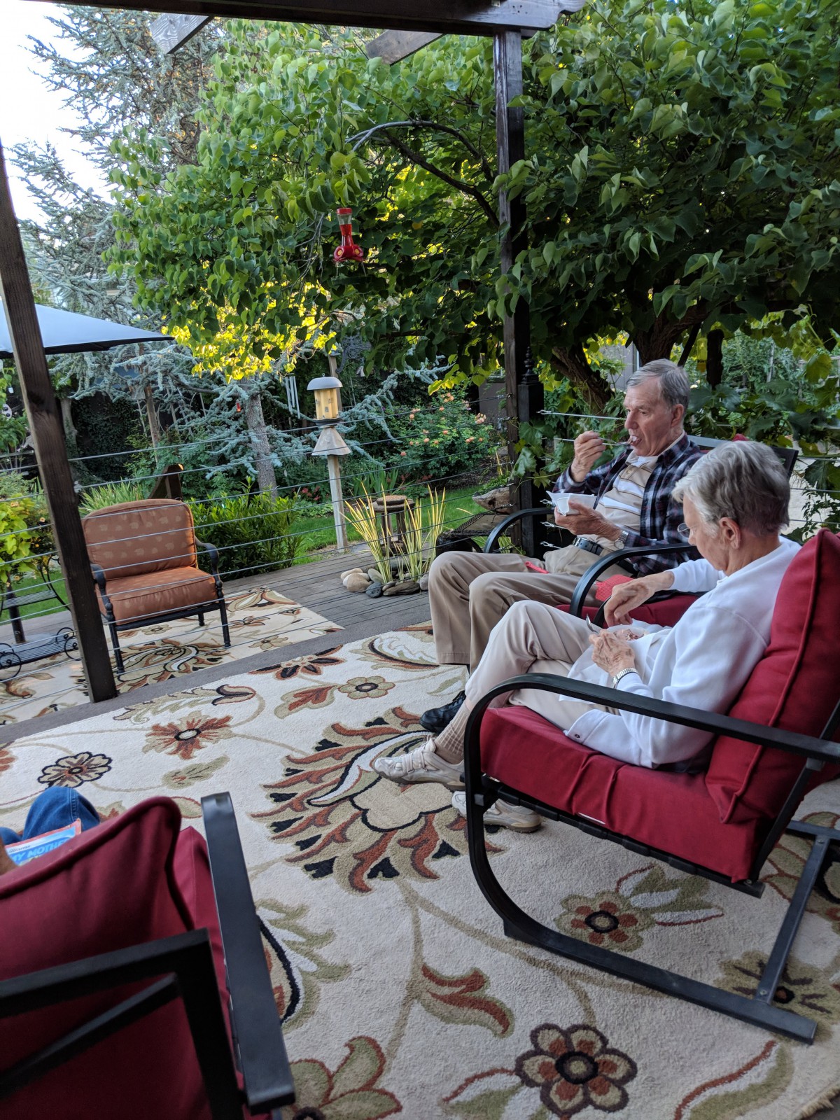 A family relaxing on a patio surrounded by lush greenery and comfortable seating.