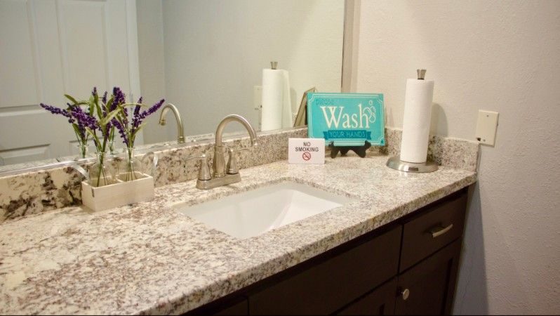 A bathroom countertop with a sink, faucet, and decorative items.