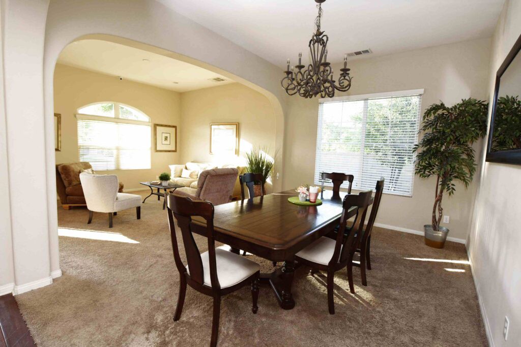 A well-lit dining room featuring a wooden table, chairs, and a decorative chandelier.