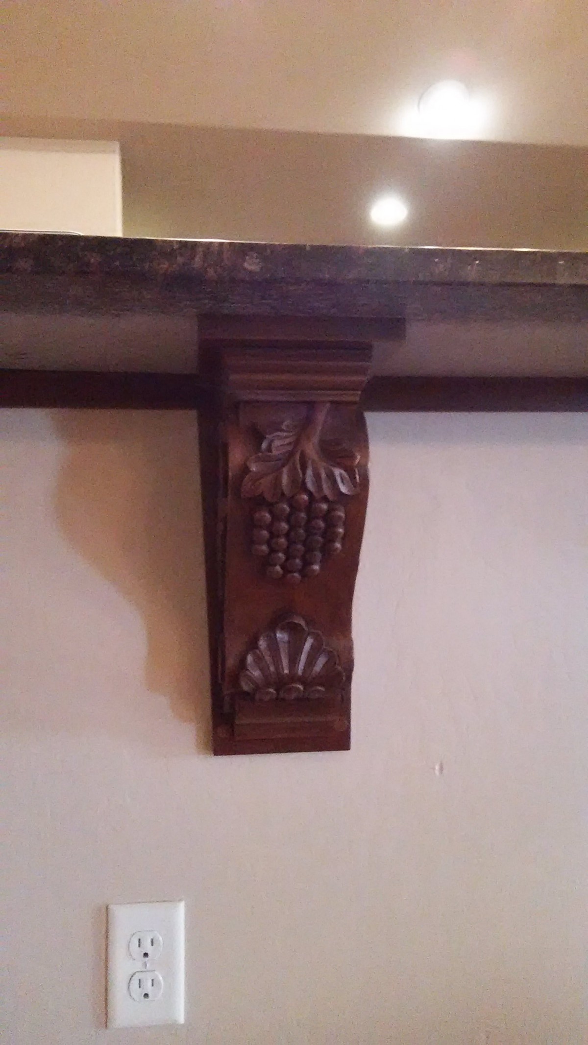 A decorative wooden corbel with intricate carvings supporting a shelf.
