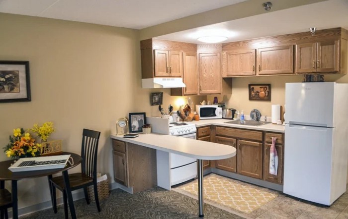 A cozy apartment kitchen with wooden cabinets, a stove, and a small dining area.