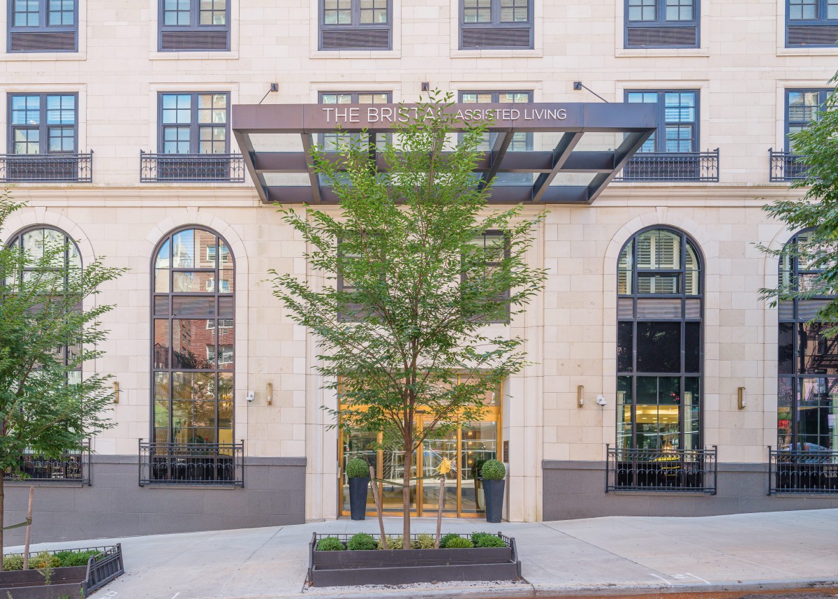 Elegant building entrance with large glass windows and a central tree.