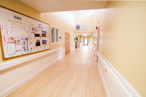 A bright and clean hallway in a healthcare facility, featuring light-colored walls and wood flooring.