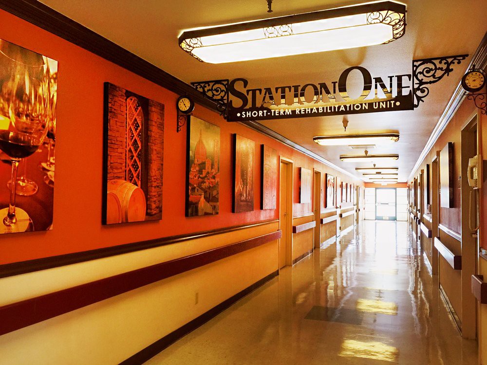 A brightly lit hospital hallway with orange walls and a sign for Station One.