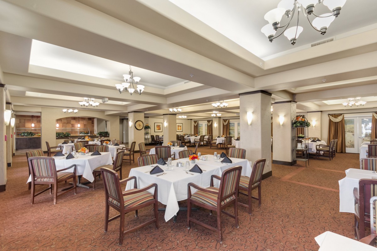 A spacious and elegantly decorated restaurant dining area with neatly arranged tables and chairs.