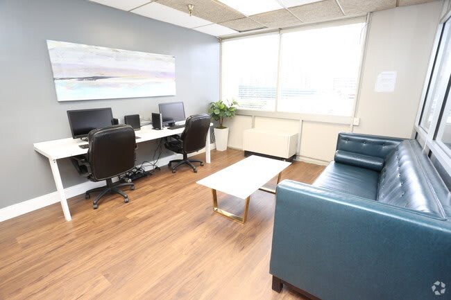 A modern office space with desks, computers, and a comfortable seating area.