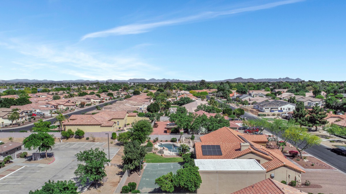 Aerial view of a suburban neighborhood with houses and solar panels on rooftops.