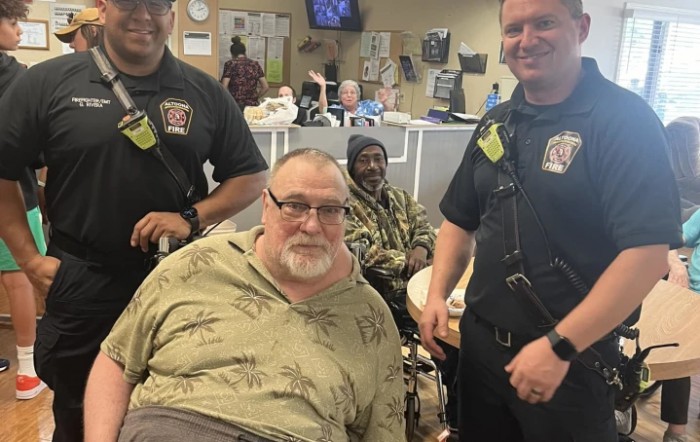 A group of people, including two in uniform, gathered indoors.