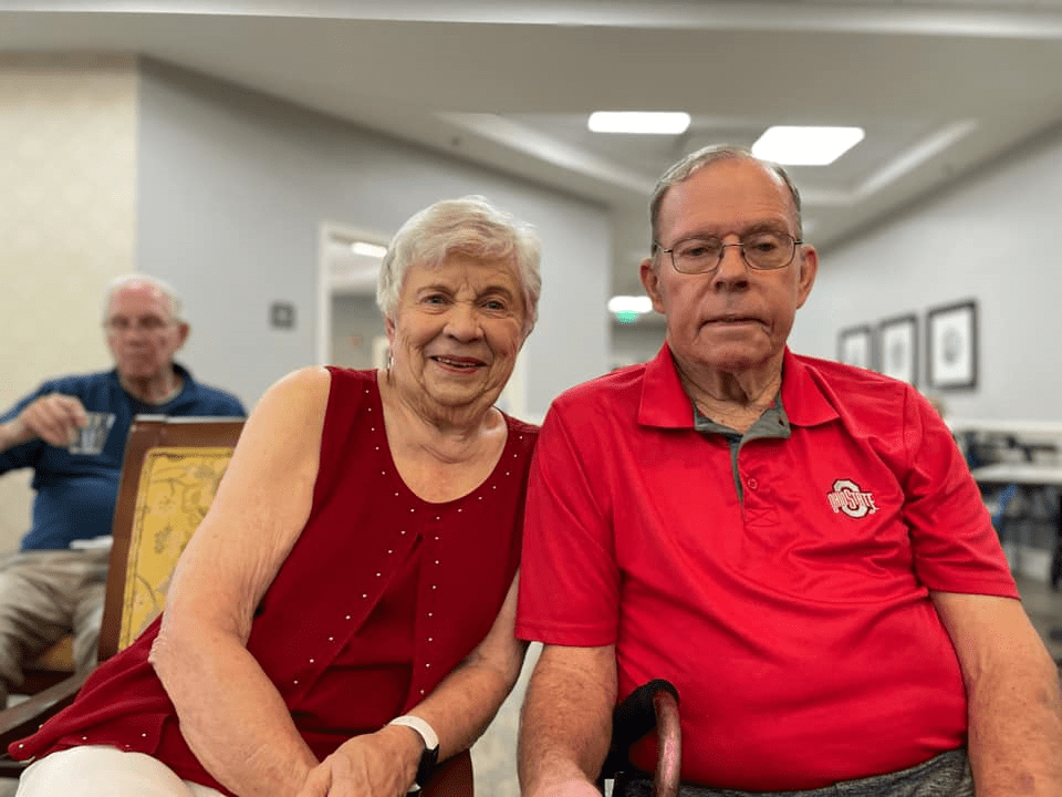 An elderly couple smiling while sitting indoors.