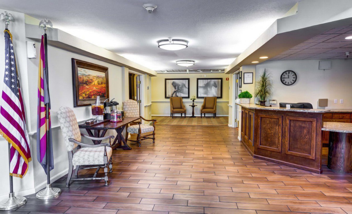 A well-lit lobby with wooden flooring, furnished with chairs and decorated with artwork.