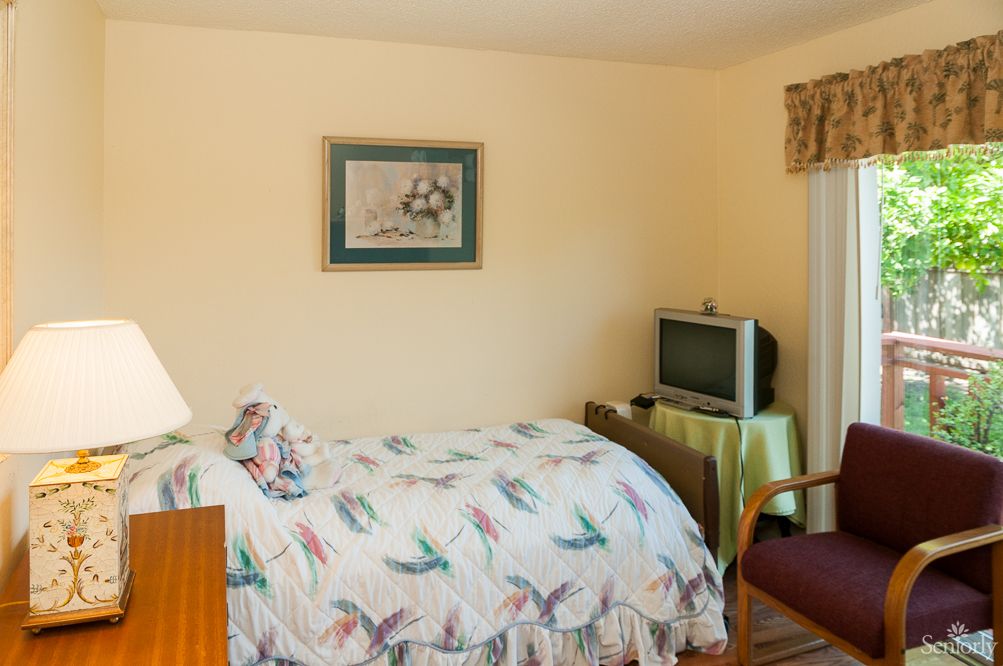 A cozy bedroom with a single bed, vintage television, and decorative painting.