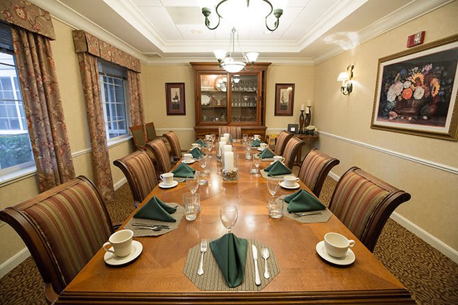 A formal dining room with an elegantly set table and a chandelier overhead.