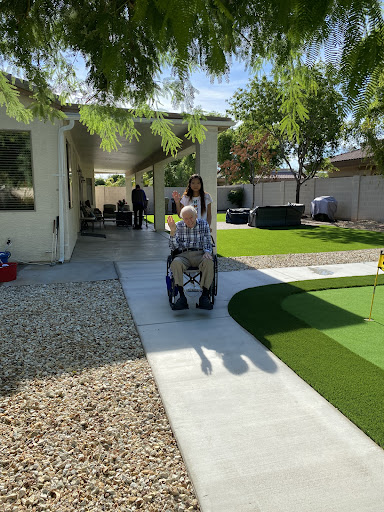 A senior individual using a wheelchair on a sunny day in a well-maintained garden.