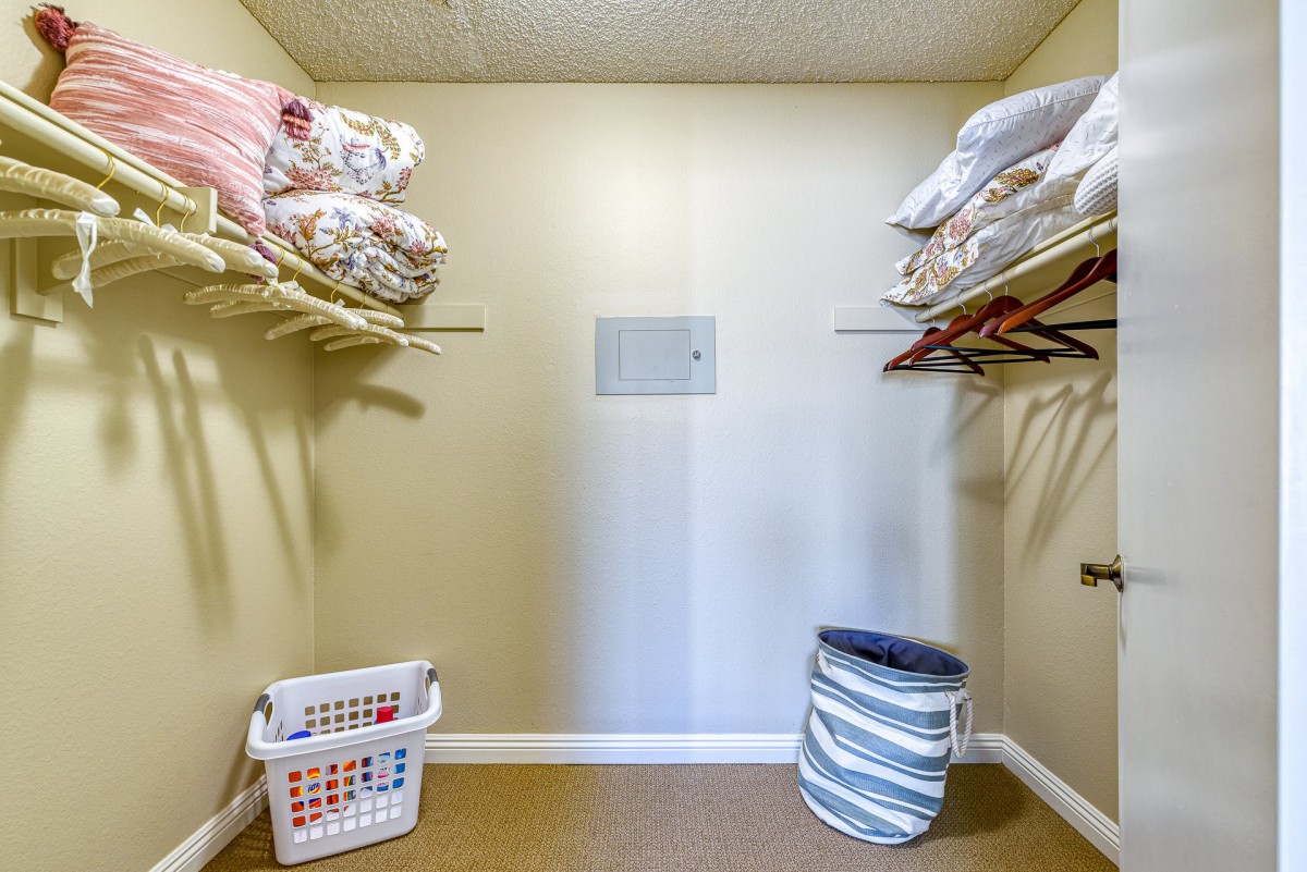 A well-organized closet featuring shelves with neatly stacked linens and laundry baskets on the floor.