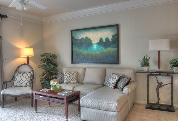A cozy living room with a large painting above a comfortable sofa, complemented by a coffee table and decorative lighting.