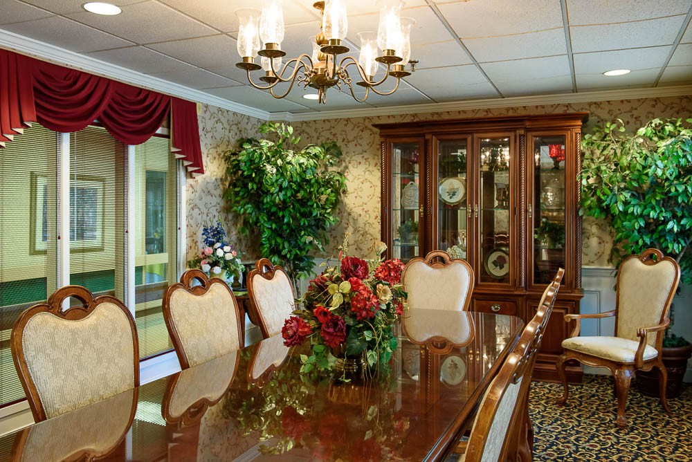 A luxurious dining room featuring an elegant chandelier, ornate wooden furniture, and a decorative floral centerpiece.