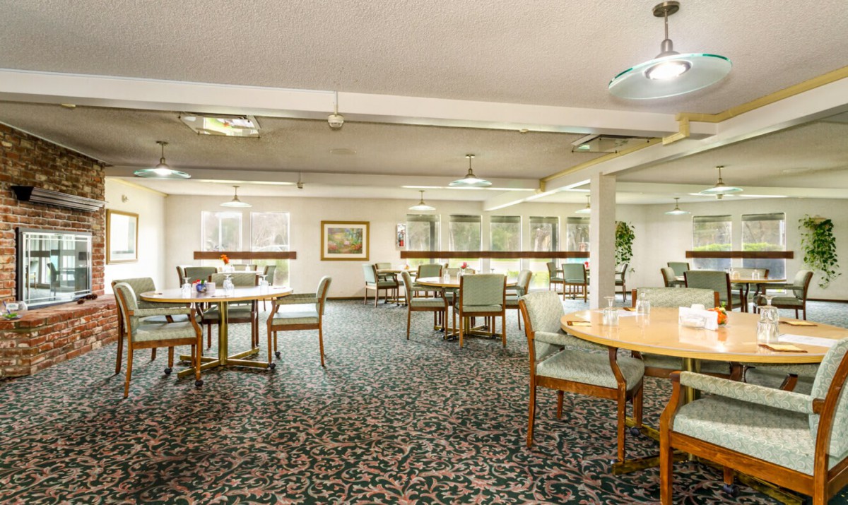 A spacious dining area with multiple tables and chairs arranged on a patterned carpet.